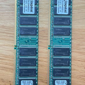 May include: Two Kingston KTA-G5400/512 RAM modules. Each green circuit board features multiple Infineon chips and the text "ASSY IN USA". The modules are designed for computer memory upgrades.