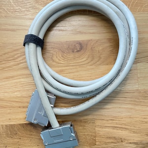 May include: A gray computer cable with two silver connectors. The cable is coiled and has text printed on it that reads "LOW VOLTAGE COMPUTER CABLE" and "AWM 80°C 30V VW-1 1004".