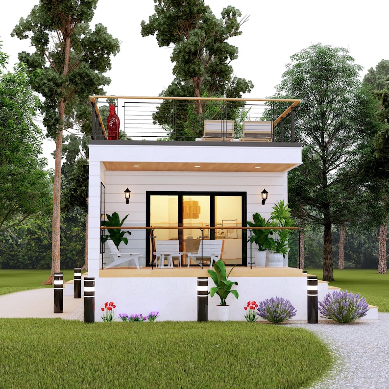 May include: A modern, white two-story house with a rooftop deck, surrounded by lush greenery. The house features a balcony with seating, a red decorative vase, and a pathway leading to the entrance. The exterior is decorated with plants and lights.