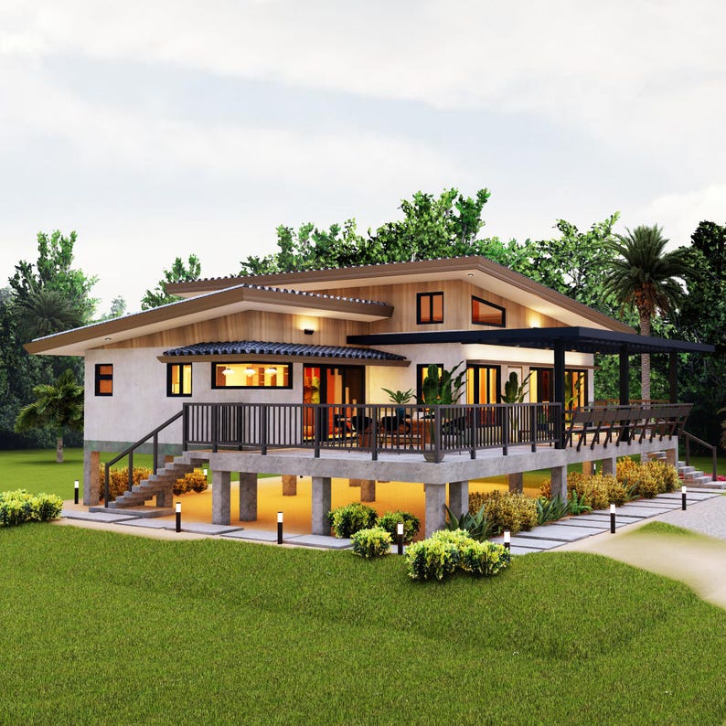 Op de afbeelding: Een modern, eenlaags huis met een houten terras en een betonnen fundering. Het huis heeft een witte buitenkant met bruine afwerking en grote ramen. Het terras is omgeven door weelderig groen landschap.