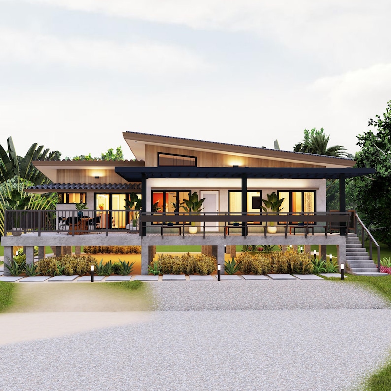 Op de afbeelding: Een modern, eenlaags huis met een schuin dak en een groot overdekt terras. Het huis staat op pilaren en heeft een betonnen oprit.