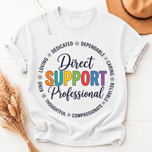 Peut inclure: Un t-shirt blanc à manches courtes avec un motif circulaire portant le texte Direct SUPPORT Professional en lettres colorées. Le texte environnant inclut les mots Loving, Dedicated, Dependable, Caring, Reliable, Compassionate, Thoughtful et Kind.
