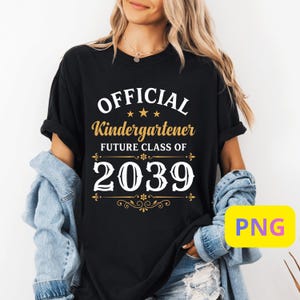 Peut inclure: T-shirt noir avec l'inscription "OFFICIAL Kindergartener FUTURE CLASS OF 2039" en lettres blanches et dorées. Le t-shirt a des manches retroussées et est porté avec une veste en jean.