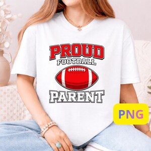 Puede incluir: Camiseta blanca con las palabras "PROUD FOOTBALL PARENT" en letras rojas y negras. Un gráfico de fútbol americano rojo y blanco está centrado debajo de la palabra "FOOTBALL".