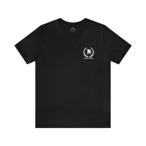 Op de afbeelding: Zwart T-shirt met een witte afbeelding van een Spartaanse helm in een lauwerkrans. De tekst "MEAN STREAK" staat onder de afbeelding.