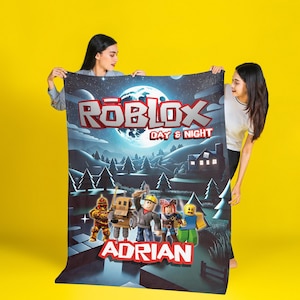 K&ouml;nnte beinhalten: Eine rechteckige Fleecedecke mit einem Roblox Day & Night-Motiv, einem gro&szlig;en Mond, einer Waldlandschaft und f&uuml;nf Spielfiguren. Der Text Roblox Day & Night steht oben und der Name Adrian ist unten in roter Schrift aufgedruckt.