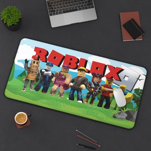 Könnte beinhalten: Eine farbenfrohe Mauspad mit dem Wort "ROBLOX" in roten Buchstaben und einer Gruppe von Comicfiguren aus dem beliebten Online-Spiel. Die Figuren stehen auf einem grünen Grasfeld mit blauem Himmel im Hintergrund.