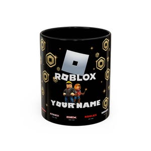 Pode incluir: Caneca de cerâmica preta com um logotipo Roblox e um padrão de moedas de ouro. A caneca apresenta dois personagens Roblox e o texto "Your Name".