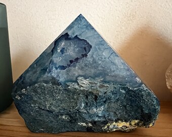 May include: A blue and white agate crystal pyramid with a rough, natural texture. The crystal has a unique, swirling pattern and is a beautiful example of natural beauty.