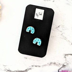 May include: A white ceramic mug with a black handle and the text "But First, Coffee" in a black, handwritten-style font. The mug is on a white surface.