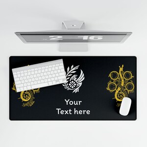 Op de afbeelding: Zwarte rechthoekige bureaumat met een wit toetsenbord, muis en computermonitor. De mat heeft gouden en witte decoratieve ontwerpen en de tekst "Your Text here".