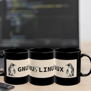 Könnte beinhalten: Drei schwarze Kaffeetassen mit einem weißen Band mit einer Pinguin-Illustration und dem Text "GNU Linux". Die Tassen stehen auf einer Holzoberfläche mit einem Laptop und einer Tastatur im Hintergrund. Die Tassen sind für Computer-Enthusiasten.