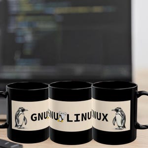 Könnte beinhalten: Drei schwarze Kaffeetassen mit einem weißen Band mit dem Text "GNU Linux" und einer Pinguin-Illustration. Die Tassen stehen auf einer Holzoberfläche mit einem Laptop und einer Tastatur im Hintergrund.