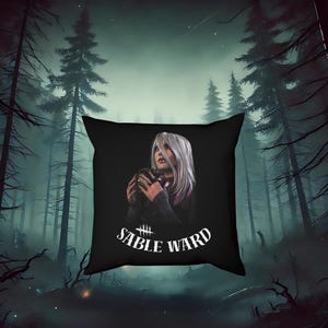 May include: Black square pillow featuring a digital illustration of a woman with white hair and a dark outfit, holding a small object. The pillow has the text "SABLE WARD" in white, with a forest background.