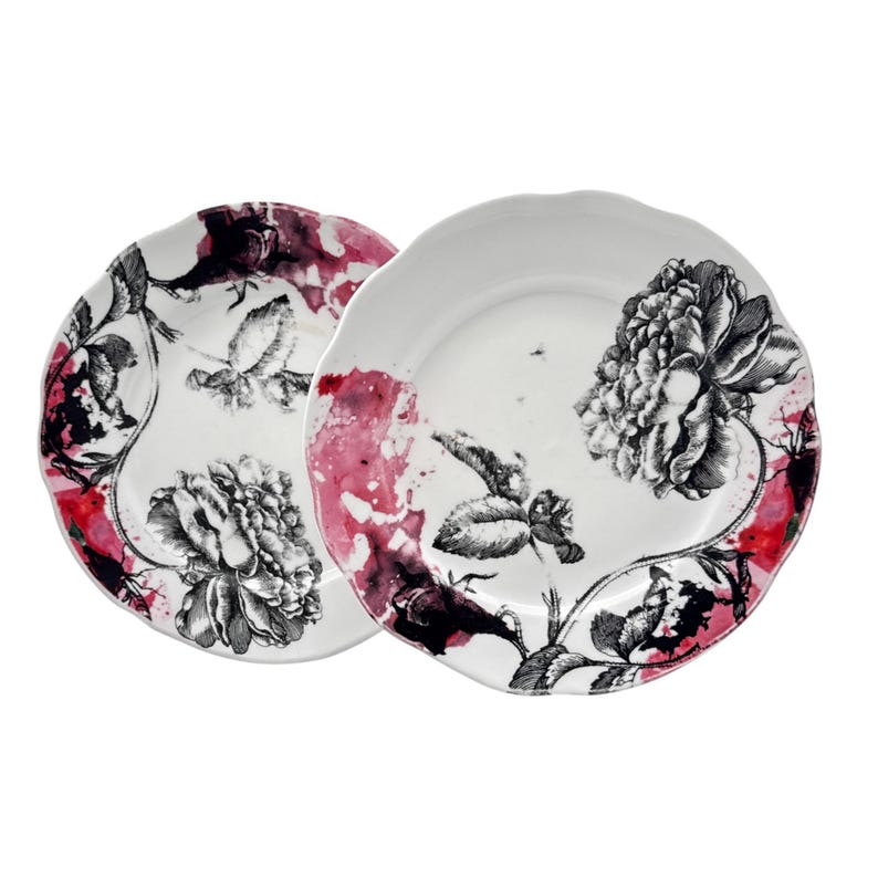 K&ouml;nnte beinhalten: Zwei wei&szlig;e Keramikteller mit floralem Design. Die Teller zeigen eine schwarz-wei&szlig;e Pfingstrosen- und Bl&auml;tterillustration mit roten und rosa Aquarellakzenten. Die Teller haben einen gewellten Rand.