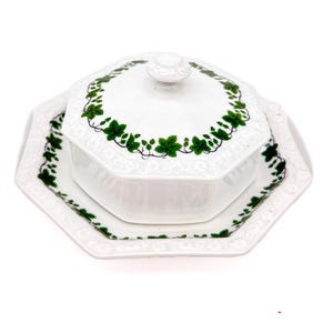 May include: White ceramic serving dish with a lid and a matching plate. The dish and lid are decorated with a green ivy leaf pattern around the edges. The set has an octagonal shape and a raised, decorative border.