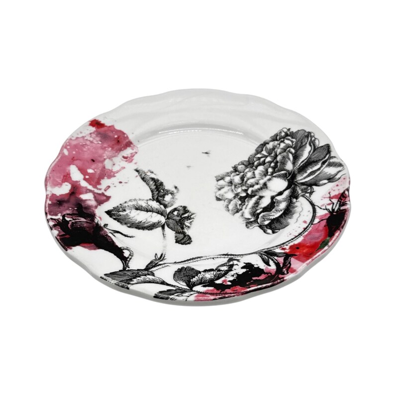 K&ouml;nnte beinhalten: Wei&szlig;er Keramikteller mit gewelltem Rand. Der Teller hat ein schwarz-wei&szlig;es Blumendesign mit einer gro&szlig;en Pfingstrose und kleineren Blumen. Farbspritzer in Rot und Rosa setzen farbliche Akzente.