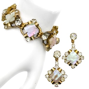 May include: A vintage jewelry set featuring a bracelet and matching earrings. The set has a gold-tone metal setting with square mother-of-pearl insets and clear rhinestone accents. The bracelet is linked, and the earrings are drop style.