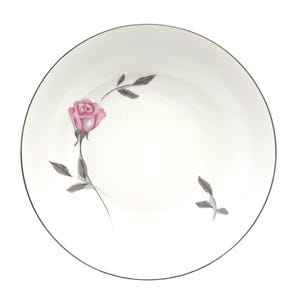 May include: A round white ceramic plate featuring a single pink rose with grey stems and leaves. The plate has a thin silver rim around the edge. The floral design is positioned on the left side, with a small sprig of grey leaves on the right.