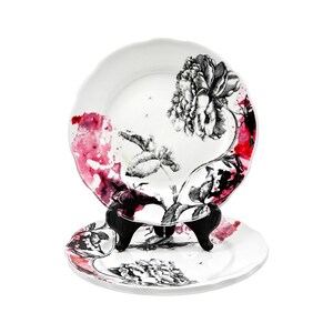 K&ouml;nnte beinhalten: Zwei wei&szlig;e Keramikteller mit floralem Design. Die Teller zeigen eine schwarz-wei&szlig;e Pfingstrosen-Illustration mit roten und rosa Aquarellakzenten. Ein Teller wird auf einem schwarzen St&auml;nder pr&auml;sentiert.