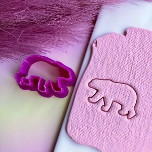May include: A purple plastic bear cookie cutter and a pink clay bear cutout.