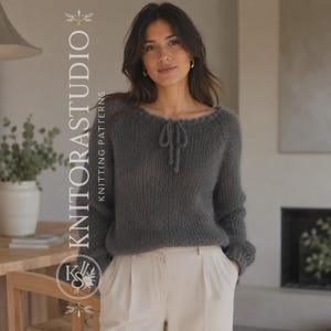 May include: A dark gray long-sleeved knit sweater featuring a round neckline with a decorative tie detail. The sweater has a loose, textured knit construction and is paired with light-colored trousers. The text KNITORASTUDIO KNITTING PATTERNS is visible.
