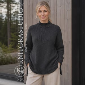 Pode incluir: Uma camisola de manga comprida cinzento-carvão escuro com gola alta, punhos canelados e uma bainha canelada com um design curvo assimétrico. O texto KNITORASTUDIO KNITTING PATTERNS está impresso verticalmente no lado esquerdo da imagem.