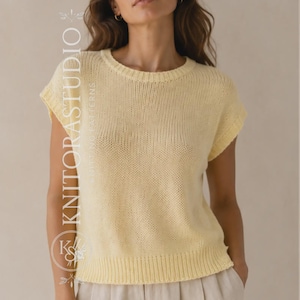Può includere: Un maglione in maglia giallo pallido a maniche corte con scollo rotondo e bordi a coste su colletto, maniche e orlo. Il testo KNITORSTUDIO KNITTING PATTERNS è stampato verticalmente in bianco sul lato sinistro del capo.