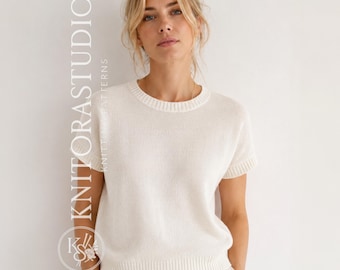 Può includere: Un maglione in maglia color crema a maniche corte con scollo rotondo e bordi a coste su colletto, maniche e orlo. Il testo KNITORASTUDIO KNITTING PATTERNS è visualizzato verticalmente sul lato sinistro dell'immagine in lettere bianche.