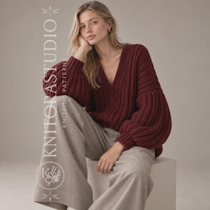 Op de afbeelding: Een dieprode V-hals trui met een grove ribgebreide textuur en lange, volumineuze mouwen, gecombineerd met een lichtbeige broek met wijde pijpen. De afbeelding bevat de verticale tekst KNITORASTUDIO KNITTING PATTERNS en een cirkelvormig logo.