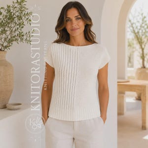 Könnte beinhalten: Ein kurzärmeliges, cremeweißes Strickoberteil mit geteiltem Design, das auf einer Seite eine vertikale Rippenstruktur und auf der anderen eine glatte Strickstruktur aufweist. Das Kleidungsstück hat einen weiten, runden Ausschnitt und einen gerippten Saum, kombiniert mit einer hellen Hose.