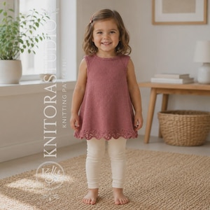 May include: A sleeveless, dusty rose-coloured knitted tunic featuring a delicate scalloped lace hem and a round neckline. The garment is paired with plain, off-white leggings. The text KNITORAS STUDIO KNITTING PATTERNS is visible on the left.