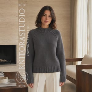 Può includere: Un maglione a maniche lunghe grigio scuro con collo alto, polsini e orlo a coste. Il maglione presenta maniche raglan e una texture in maglia tinta unita. Il testo KNITORASTUDIO KNITTING PATTERNS è visibile sul lato sinistro dell'immagine.