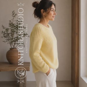 Może przedstawiać: Bladoż&oacute;łty sweter z długim rękawem, z prążkowanym karczkiem i mankietami, zestawiony z białymi spodniami. Tekst KNITORASTUDIO KNITTING PATTERNS oraz okrągłe logo są widoczne po lewej stronie obrazu, obok rośliny w doniczce.