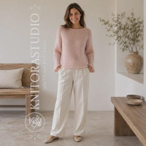 Può includere: Un morbido maglione a maniche lunghe color rosa pallido con scollo rotondo e una finitura in maglia testurizzata e soffice. Il maglione è abbinato a pantaloni color crema dal taglio ampio, gamba dritta e piega frontale ben definita.