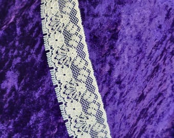 May include: White lace trim with a delicate floral pattern against a purple velvet background.