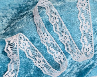 May include: White lace trim with a delicate floral pattern on a teal blue velvet fabric.