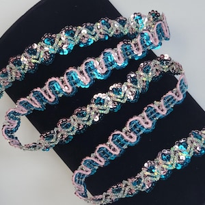 May include: Teal and pink sequined trim with a wavy design. The trim is made of small sequins and beads.