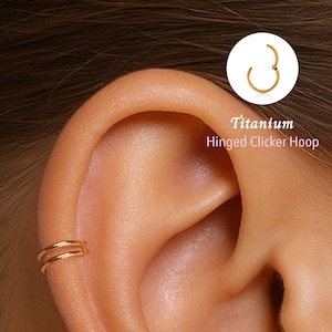 Könnte beinhalten: Nahaufnahme eines Ohrs mit zwei goldfarbenen Creolen. Ein kleiner, goldfarbener Klappcreolen-Reifen wird in einem weißen Kreis mit dem Text "Titanium Hinged Clicker Hoop" gezeigt.