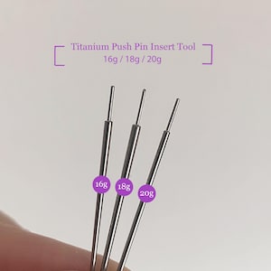 May include: Three silver titanium push pin insert tools, labelled 16g, 18g, and 20g. The text "Titanium Push Pin Insert Tool 16g / 18g / 20g" is above the tools. The tools are on a white background.
