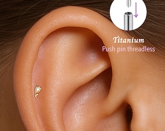 May include: Close-up of a person's ear with a small gold flower push pin earring. The earring is made of titanium and is threadless. The text "Titanium Push pin threadless" is visible in the image.