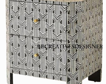 May include: A black and white geometric patterned nightstand with two drawers and gold knobs. The nightstand has a modern design and is made of bone inlay.