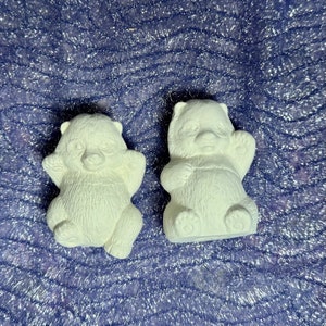 May include: Two white ceramic panda bear figurines. The panda bears are sitting with their arms raised.