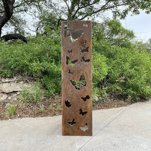 May include: A rusty metal butterfly garden art piece with cut-out butterfly shapes. The piece is standing upright on a concrete surface.