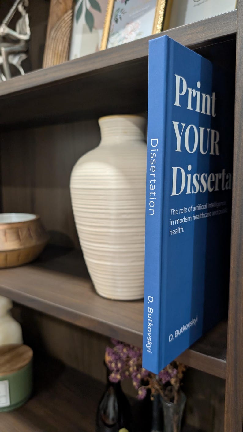 Puede incluir: Un libro azul titulado "Print YOUR Dissertation" con texto blanco, de pie sobre una estanter&iacute;a de madera. El lomo del libro dice "Dissertation" verticalmente. El libro trata sobre la inteligencia artificial en la atenci&oacute;n m&eacute;dica. Otros elementos decorativos son visibles.