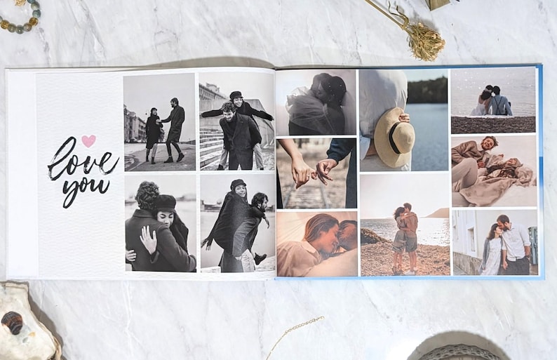 May include: Open photo album with a collage of black and white photos of couples. The album's left page has the words "Love you" with a pink heart. The right page has a blue border.