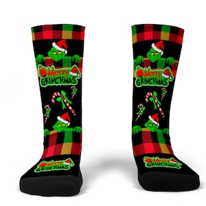 May include: A pair of black and green Christmas themed socks with a red and green plaid pattern. The socks feature a Grinch character with the text "Merry Grinchmas".