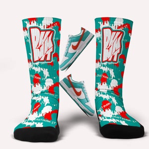 May include: Knee-high socks with a teal, white, and red pattern. The socks display the text "JUST DUNK IT" and a graphic. Two pairs of teal and orange trainers are also in the image.