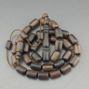 May include: A dark brown wooden prayer beads or rosary with a tassel. The beads are cylindrical and have a smooth, polished finish.