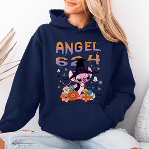 May include: Navy blue hooded sweatshirt featuring a graphic of a pink alien character wearing a witch hat, surrounded by flowers and the text "ANGEL 624". The design has orange, purple, and white accents, with Halloween-themed elements.